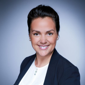 Portrait of a person in formal attire, smiling at the camera against a blue gradient background.