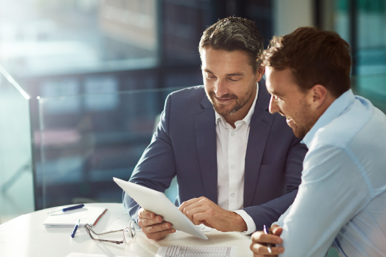 Two male professionals discussing talent mapping on a device during a meeting