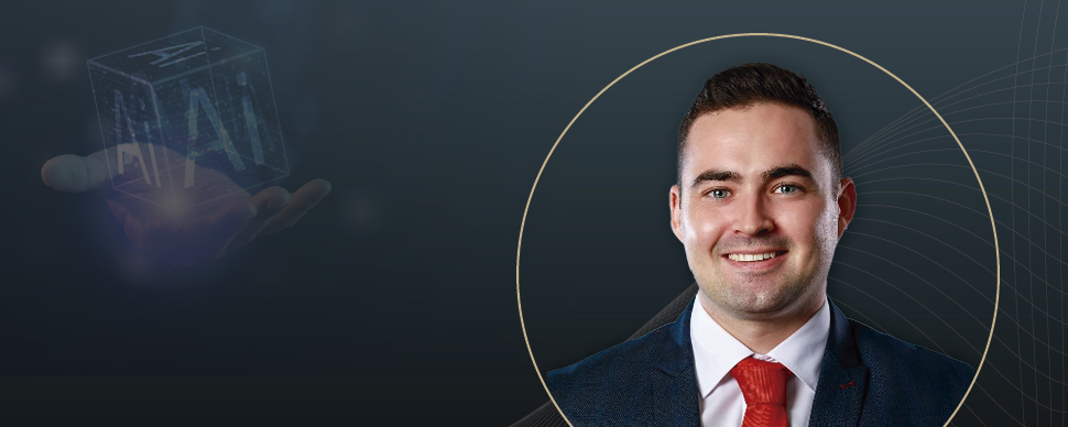 A professional portrait of a smiling man in a suit and red tie, overlaid on a dark background featuring subtle graphic lines and a futuristic hologram of "AI" in a cube held by a hand.