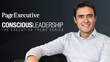 Person sitting on a green couch with a conscious leadership series backdrop.