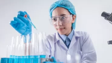 Scientist wearing protective gear working with test tubes in a laboratory.