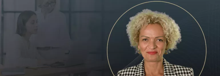  A professional portrait of a woman with curly blonde hair, wearing a patterned blazer, overlaid on a dark background with subtle graphic lines and the faint image of two women working on a laptop in the background.