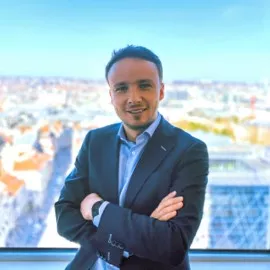 Person smiling in front of a city skyline.